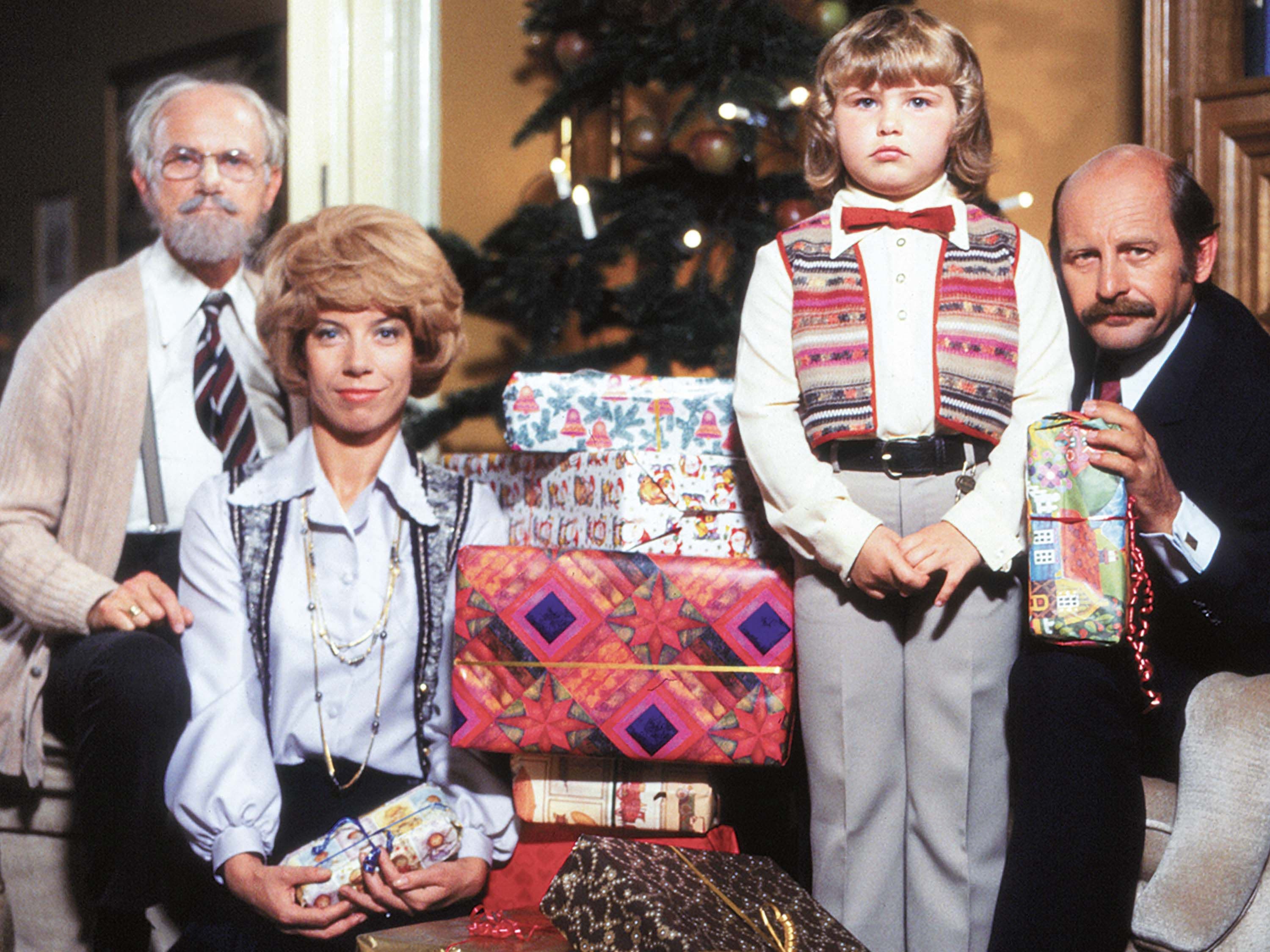 Vier Personen posieren für ein Weihnachtsfoto vor einem geschmückten Weihnachtsbaum und verpackten Geschenken. | Bildquelle: ©1997 Radio Bremen | OneGate Media GmbH Vier Personen posieren für ein Weihnachtsfoto vor einem geschmückten Weihnachtsbaum und verpackten Geschenken.